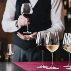 Sommelier presenting red wine among stemmed glasses