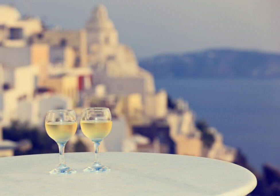 Two wine glasses on table overlooking seaside village
