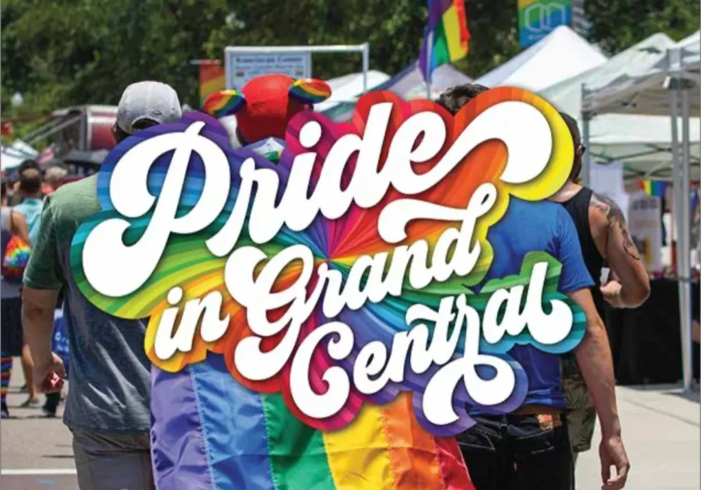 Crowd at outdoor Pride festival with rainbow flag