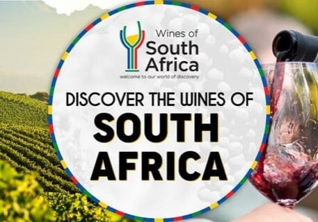Glass of red wine being poured beside vineyard